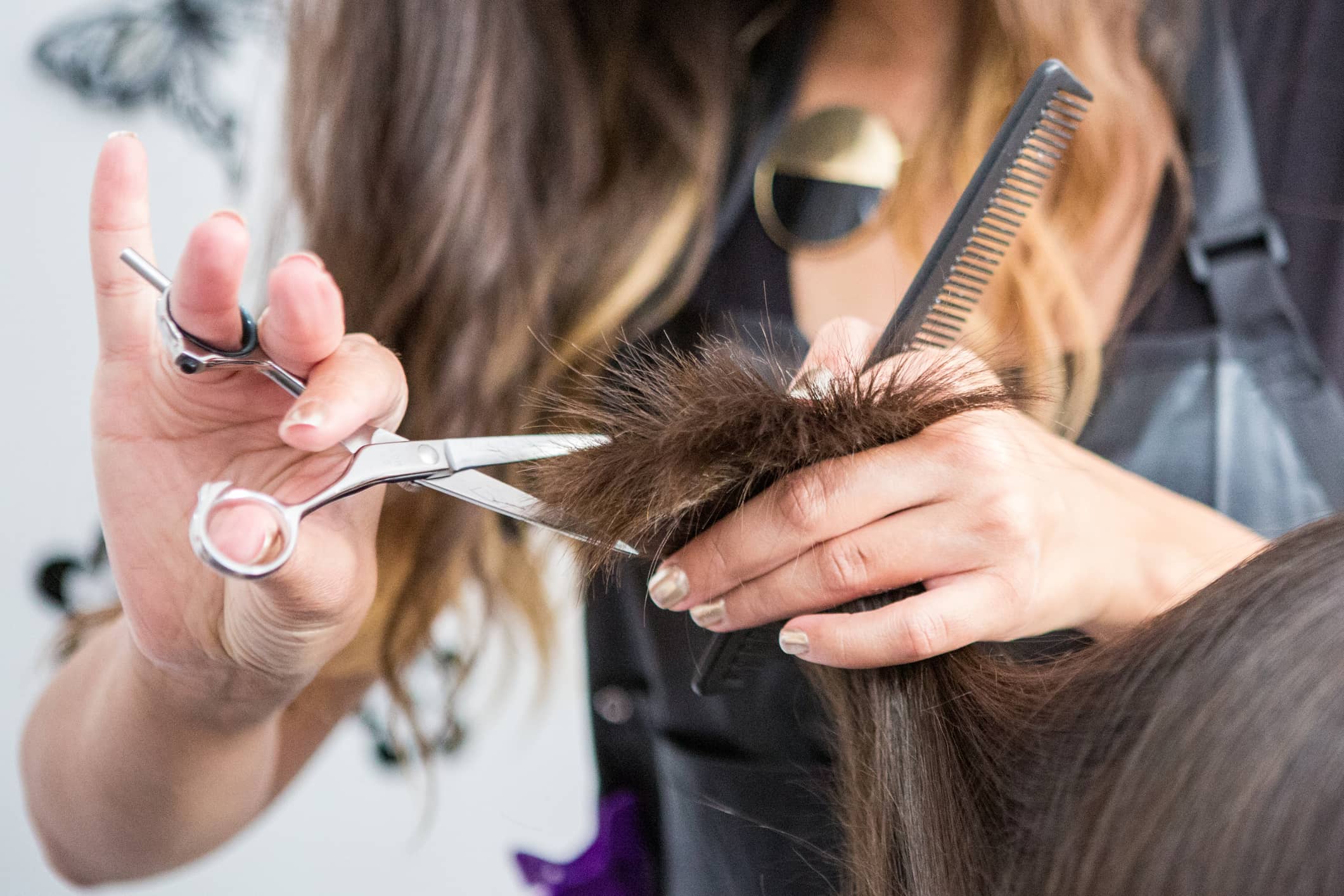 Hairstylist trims a client’s hair with scissors, using a comb for precision.
